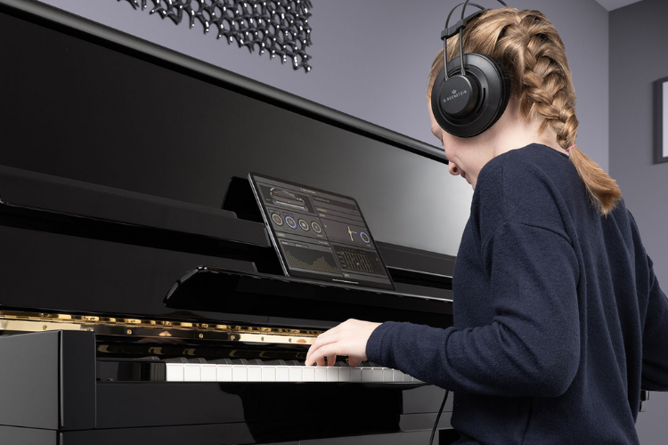 Girl playing acoustic silent piano with headphones and ipad