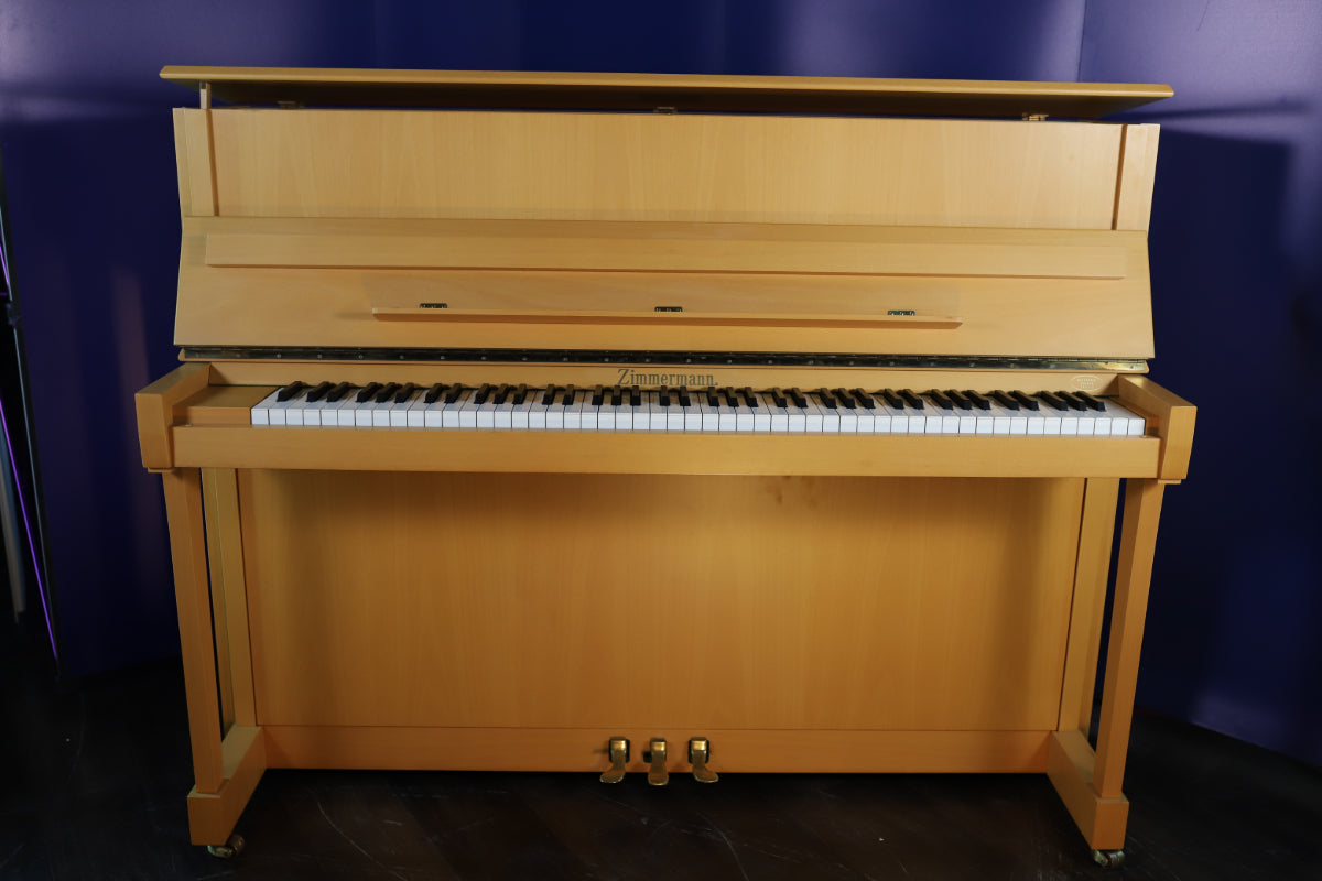 Wooden Zimmermann upright piano in light oak against a blue wall